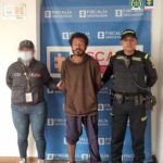 En la fotografía aparece el capturado junto a un servidor del CTI y un agente de la Policía Nacional. En la parte superior está un banner de la Fiscalía General