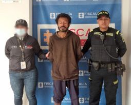 En la fotografía aparece el capturado junto a un servidor del CTI y un agente de la Policía Nacional. En la parte superior está un banner de la Fiscalía General