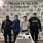 En la imagen están los 2 hombres asegurados con servidores de la Policía Nacional a los lados