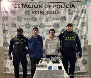 En la imagen están los 2 hombres asegurados con servidores de la Policía Nacional a los lados