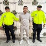 Foto del detenido con dos agentes de la Policía Nacional custiodíandolo. En el fondo, backing de la Policía Nacional.Foto del detenido con dos agentes de la Policía Nacional custiodíandolo. En el fondo, backing de la Policía Nacional.