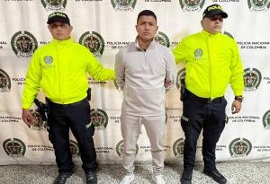 Foto del detenido con dos agentes de la Policía Nacional custiodíandolo. En el fondo, backing de la Policía Nacional.Foto del detenido con dos agentes de la Policía Nacional custiodíandolo. En el fondo, backing de la Policía Nacional.