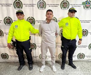 Foto del detenido con dos agentes de la Policía Nacional custiodíandolo. En el fondo, backing de la Policía Nacional.Foto del detenido con dos agentes de la Policía Nacional custiodíandolo. En el fondo, backing de la Policía Nacional.