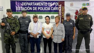 en la imagen tres personas detenidas bajo custodia de investigadores del CTI y uniformados de la Policía Nacional. Detrás suyo un backing institucional.