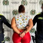 Se observa a la capturada de espaldas junto a dos uniformados de la Policía Nacional.  Detrás se observa el banner de la Policía Nacional.