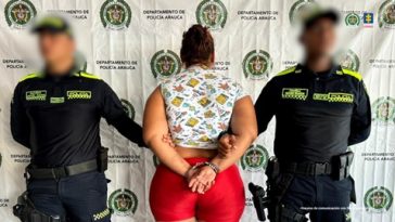 Se observa a la capturada de espaldas junto a dos uniformados de la Policía Nacional.  Detrás se observa el banner de la Policía Nacional.