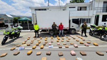 El capturado se encuentra custodiado por tres uniformados de la Policía Nacional. En la foto se observa el estupefaciente incautado y de fondo se ve el carro en el que iría camuflado el alcaloide.