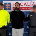 Se observa al capturado de frente, a un costado un funcionario del Cuerpo Técnico de Investigación CTI y al otro uno de Policía Nacional. Atrás un pendón de Fiscalía General de la Nación