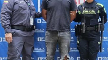 En la fotografía aparece de pie y con los brazos atrás Julio Alejandro Benavídez Martínez. Viste camiseta de manga corta de color gris oscuro, jean de color gris y zapatillas azules. Al lado derecho de él hay un servidor del CTI de la Fiscalía y a su izquierda una uniformada de la Policía Nacional. Detrás de ellos hay un pendón institucional de la Fiscalía.