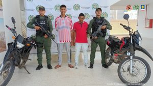 En la fotografía aparecen dos hombres capturados, acompañados de uniformados del Gaula Militar y de la Policía Nacional.  En la parte posterior un banner con logos de la entidad.