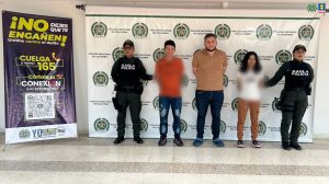 Los capturados se encuentran en custodia por dos uniformados del Gaula de la Policía Nacional. Detrás se observa un backing de la Policía Nacional.