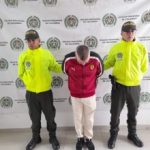 en la imagen se ve una persona detenida bajo custodia de dos uniformados de la Policía Nacional.