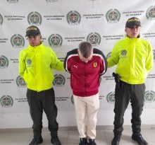 en la imagen se ve una persona detenida bajo custodia de dos uniformados de la Policía Nacional.