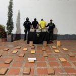 Los capturados están esposados, de espalda a la cámara, custodiados por uniformados de la Policía y en el suelo los paquetes del alucinógeno.