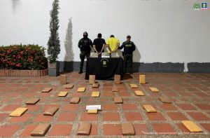 Los capturados están esposados, de espalda a la cámara, custodiados por uniformados de la Policía y en el suelo los paquetes del alucinógeno.