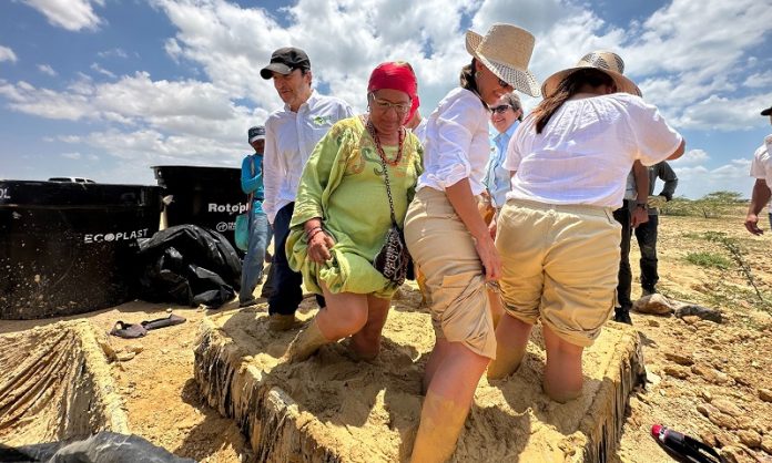 Un grupo de los funcionarios de las empresas aportantes del proyecto, junto con una wayuu, metidos dentro de un lodo, jugando para recibir energías positivas