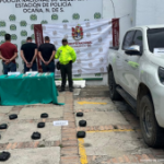 Se visualiza a los capturados de espaldas junto a dos uniformados de la Policía Nacional. Frente a ellos la sustancia estupefaciente y elementos incautados. Detrás de ellos los banners que identifican a la Policía y Ejército Nacional.