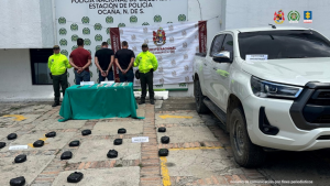 Se visualiza a los capturados de espaldas junto a dos uniformados de la Policía Nacional. Frente a ellos la sustancia estupefaciente y elementos incautados. Detrás de ellos los banners que identifican a la Policía y Ejército Nacional.