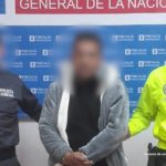 En la fotografía el acusado aparece de pie. Viste una chaqueta gris y blanca, una camiseta negra; Vaqueros azul oscuro y zapatillas blancas y negras. A su lado derecho se encuentra un servidor del CTI del Ministerio Público y a su lado izquierdo un uniformado de la Policía Nacional. Detrás de ellos hay una pancarta institucional del Ministerio Público.