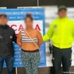 Se visualiza a la capturada junto a un investigador del CTI y un uniformado de la Policía Nacional. Detrás los banners que identifican a la Fiscalía y a la Policía Nacional