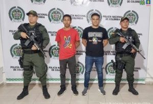 En la fotografía aparecen dos hombres capturados, acompañados de dos uniformados del Gaula de la Policía Nacional. En la parte posterior un banner con logos de la entidad.