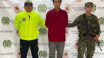 En la imagen aparece el investigado en medio de un policía y un soldado.