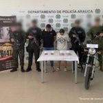 Se visualiza a los capturados junto a uniformados del Gaula Militar, Policía y Armada Nacional. Frente a ellos el dinero obtenido de la extorsión. Detrás de ellos los banners institucionales de la Policía, Armada y Ejército Nacional