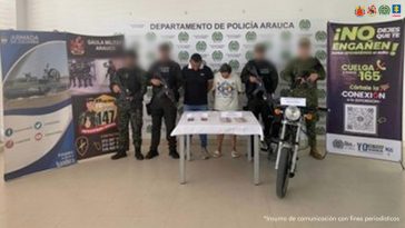 Se visualiza a los capturados junto a uniformados del Gaula Militar, Policía y Armada Nacional. Frente a ellos el dinero obtenido de la extorsión. Detrás de ellos los banners institucionales de la Policía, Armada y Ejército Nacional