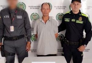 En la fotografía se aprecia de pie y con los brazos atrás a Luis Carlos Grajales Ordóñez. Viste camisa de manga corta y de cuello de color gris; pantalones oscuros y zapatos negros con zuela blanca. Al lado derecho de él hay un servidor del CTI de la Fiscalía y al lado izquierdo hay un uniformado de la Policía Nacional. Delante de ellos hay una mesa blanca cuadrada y sobre ella un letrero que dice: ‘Capturado por orden judicial’. Detrás de ellos hay un pendón institucional de la Policía.