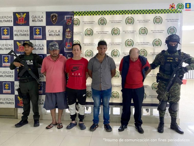 Los capturados se encuentran de frente y en custodia por uniformados del Gaula de la Policía y Ejército Nacional. Detrás hay un backing de la Policía y Ejército.