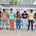 capturados de frente custodiados por policías. Detrás banner de la policía.