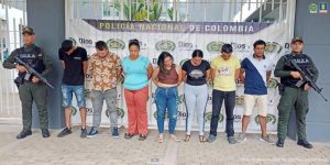 capturados de frente custodiados por policías. Detrás banner de la policía.