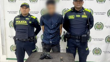 En la imagen aparece una persona de jean y camisa azul, entre dos uniformados de la Policía.