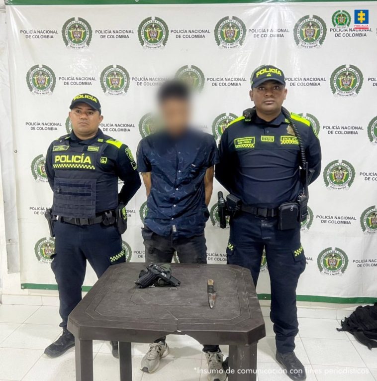 En la imagen aparece una persona de jean y camisa azul, entre dos uniformados de la Policía.