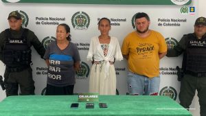 Uniformados de la Policía Nacional custodian a los hoy procesados tras su captura en Barranquilla, entre otros municipios del Atlántico.  Al fondo se ve el backing con el logo de la institución mencionada.