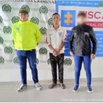 Se visualiza al capturado junto a uniformado de la Policía Nacional e investigadora del CTI. Detrás se ubican los banners que identifican a la Policía Nacional y la Fiscalía General de la Nación.