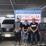 Los capturados aparecen frente a un banner de la Fiscalía y un vehículo. A cada lado aparecen servidores del CTI de la Fiscalía.