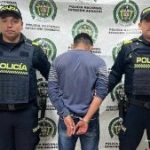 El capturado aparece  de espalda a la cámara, está custodiado por uniformados por uniformados de la Policía.