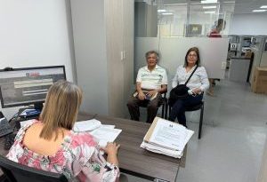 En la imagen se observan dos personas sentadas recibiendo atención por parte de una funcionaria de la Fiscalía General de la Nación