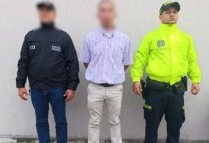 El capturado se encuentra de frente y con el rostro cubierto y custodiado por un servidor del Cuerpo Técnico de Investigación CTI y de la Policía Nacional.