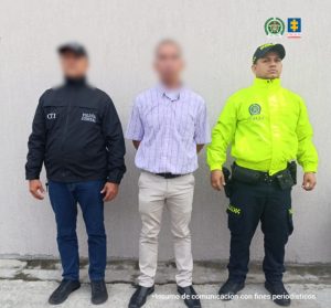 El capturado se encuentra de frente y con el rostro cubierto y custodiado por un servidor del Cuerpo Técnico de Investigación CTI y de la Policía Nacional.