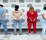 En la foto se ve a los 4 capturados de espaldas, dos hombres y dos mujeres acompañados de agentes de la Policía frente a un baking de la entidad.