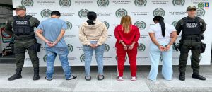 En la foto se ve a los 4 capturados de espaldas, dos hombres y dos mujeres acompañados de agentes de la Policía frente a un baking de la entidad.