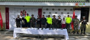 En la imagen vemos a dos personas detenidas por miembros de la policía nacional y del ejército. Frente a él hay una mesa con objetos incautados. Detrás, el apoyo institucional.