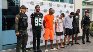 En la fotografía aparecen los 5 capturados junto a dos uniformados del Gaula de la Policía. En la parte superior está un banner de la Policía Nacional.