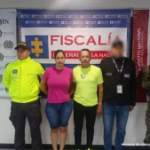 Se visualiza a los capturados junto a investigador del CTI y  uniformados de la Policía y Ejército Nacional. Detrás de ellos los banners que identifican a la Fiscalía General de la Nación y a la Policía y Ejército Nacional.