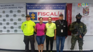 Se visualiza a los capturados junto a investigador del CTI y  uniformados de la Policía y Ejército Nacional. Detrás de ellos los banners que identifican a la Fiscalía General de la Nación y a la Policía y Ejército Nacional.