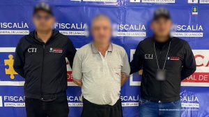 En la imagen se observa el detenido con el rostro borroso para no revictimizar a la víctima. El procesado aparece en compañía de dos uniformados de dos funcionarios del CTI