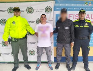 El capturado se encuentra de frente y custodiado por un servidor del Cuerpo Técnico de Investigación CTI y dos uniformados de la Policía Nacional.