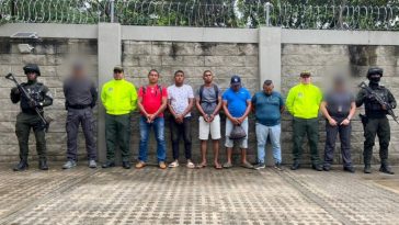 En la fotografía están los procesados de pie con los brazos hacia adelante esposados. Se encuentran acompañados de uniformados del CTI y de la Policía Nacional.